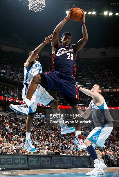 LeBron James of the Cleveland Cavaliers grabs a rebound over Marcus Thornton and Darius Songaila of the New Orleans Hornets on March 24, 2010 at the...