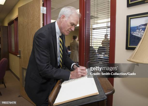 Photograph of Secretary of the Navy Richard V Spencer signing a guestbook during a visit to the Surface Warfare Officers School, Newport, Rhode...