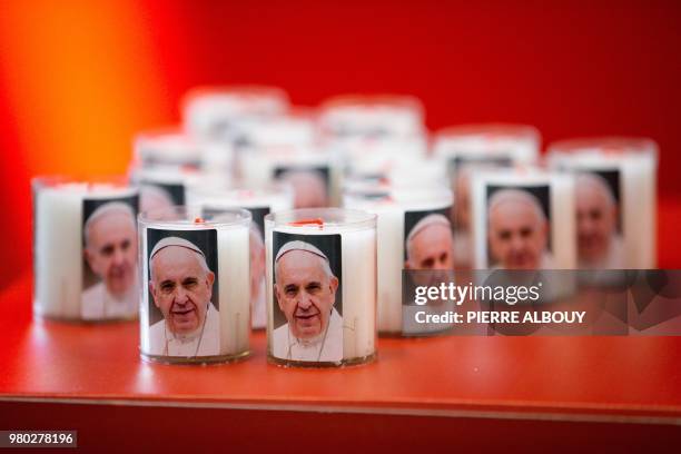 Picture taken on June 21, 2018 in Geneva shows candles bearing a picture of Pope Francis before the mass celebrated by the Pope during his one-day...