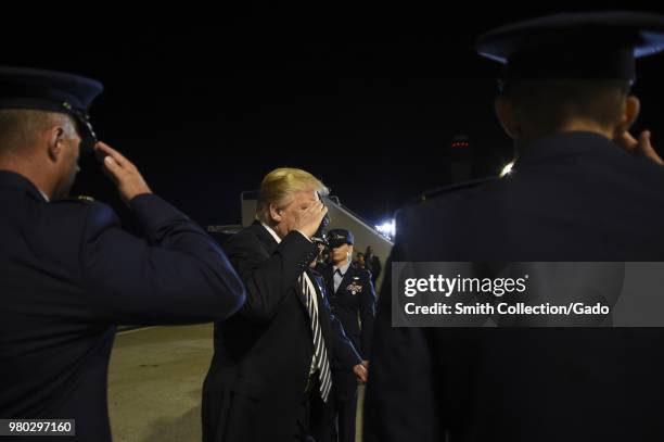 Nighttime photograph of President Donald Trump saluting at Joint Base Andrews, Maryland, prior to greeting three Americans returning from...