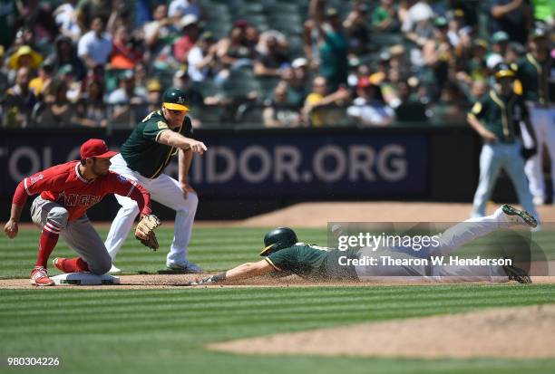 Chad Pinder of the Oakland Athletics dives into third base with a triple ahead of the throw to David Fletcher of the Los Angeles Angels of Anaheim as...