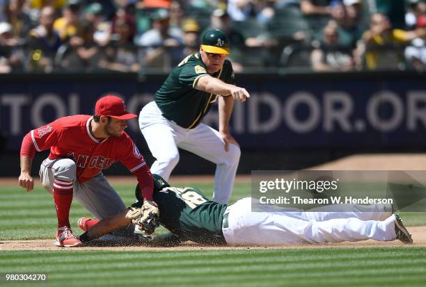 Chad Pinder of the Oakland Athletics dives into third base with a triple ahead of the throw to David Fletcher of the Los Angeles Angels of Anaheim as...