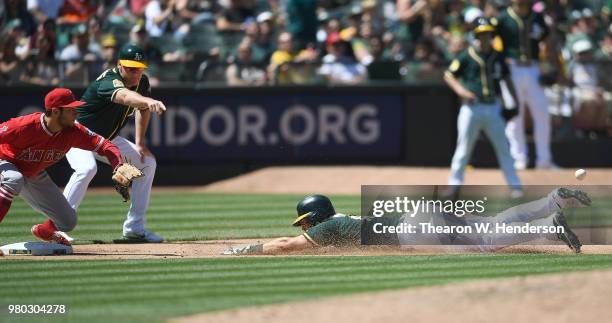 Chad Pinder of the Oakland Athletics dives into third base with a triple ahead of the throw to David Fletcher of the Los Angeles Angels of Anaheim as...