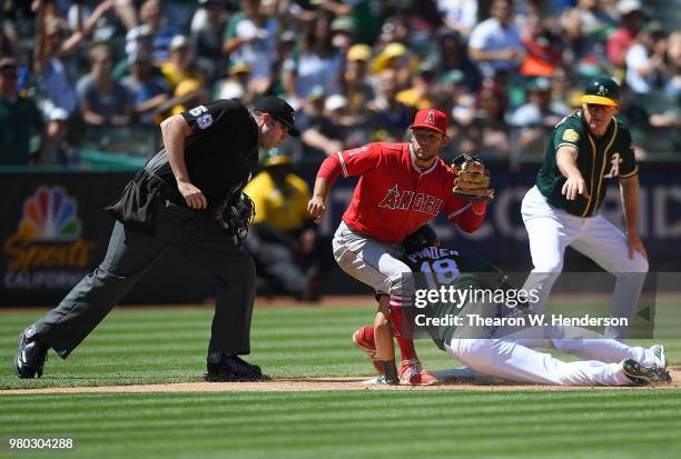 Chad Pinder of the Oakland Athletics dives into third base with a triple ahead of the throw to David Fletcher of the Los Angeles Angels of Anaheim as...