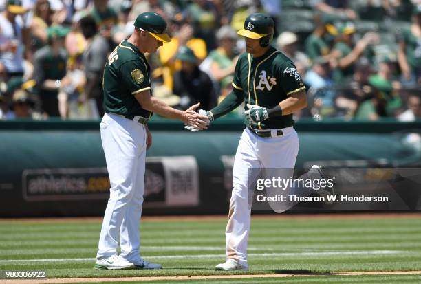 Chad Pinder of the Oakland Athletics is congratulated by third base coach Matt Williams after Pinder hit a solo home run against the Los Angeles...