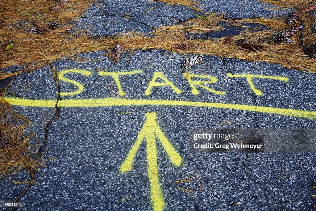 The word "start" and an arrow painted on sidewalk