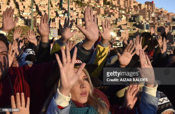 People raise their hands during a ritual at sunrise to celebrate the Aymara New Year on June 21, 2018 at the Jacha Qullu viewpoint in the outskirts...