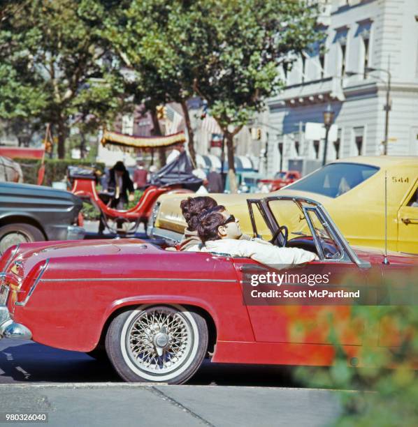 New York City - View of a couple in a red convertible sports car on a crowded street in Manhattan.