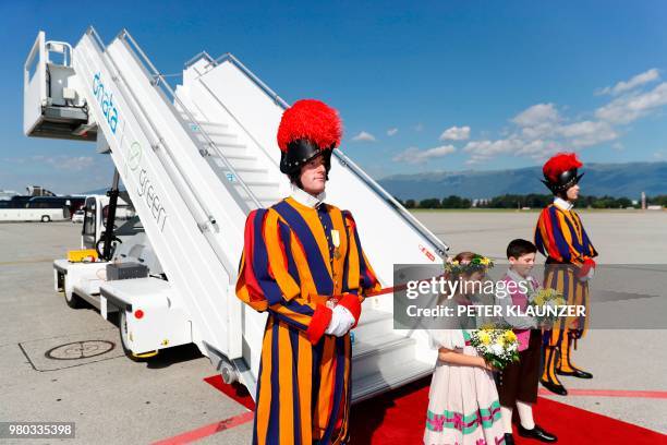Members of the Swiss guard and children with flowers wait for the arrival of the Pope at the airport during his one-day visit at the invitation of...