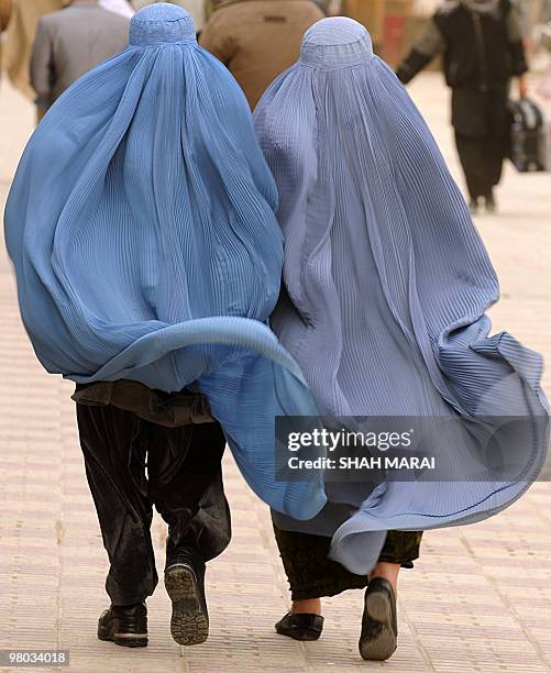 Burqa-clad Afghan woman wearing boots walks with another as they visit the Hazrat-i Ali shrine in Mazar-i-Sharif, the centre of Afghan New Year's or...