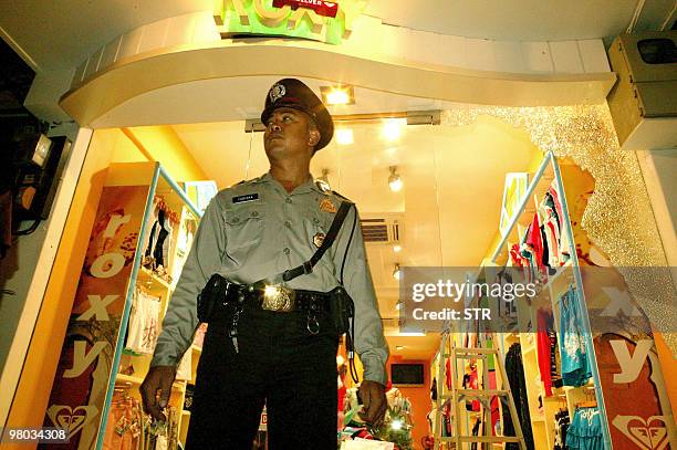 An Indonesian security officer stands in front of a shop damaged by a bomb blast in Kuta, on the island of Bali, 01 October 2005. At least 23 people...