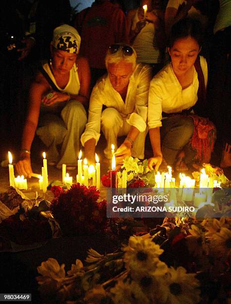 Foreign and local tourists light candles and place flowers near the site of a bomb blast in Kuta, on Bali island, 03 October 2005. At least 19...