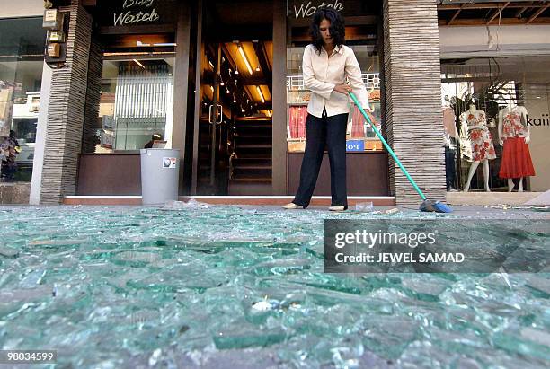 An Indonesian employee cleans shattered glasses from in front of her shop at the 01 October's bomb blast site in Kuta, on Bali island, 07 October...