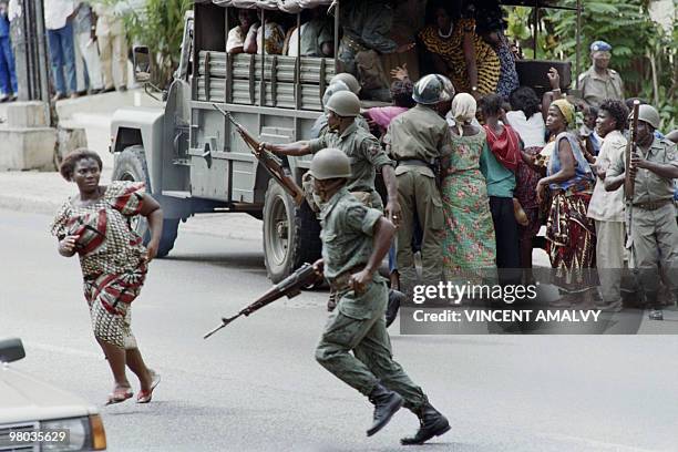 Security forces, brandishing rifles and clubs, herding a group of women onto a military truck, on October 16 in Abidjan, as Ivory Coast and many...