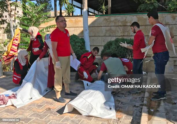 Graphic content / Members of the Syrian Civil Defence wrap in bags the bodies of victims killed in a double explosion in the northern rebel-held city...