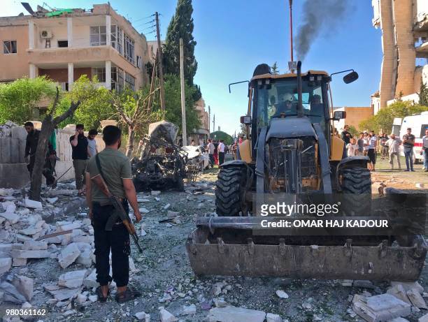 Bulldozer clears rubble at the scene of a double explosion in the northern rebel-held city of Idlib on June 21, 2018.