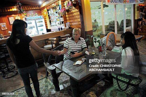 Thailand-society-marriage-Western-lifestyle,FEATURE by Rachel O'BRIEN This picture taken on January 11, 2010 shows a western man paying the bill as...