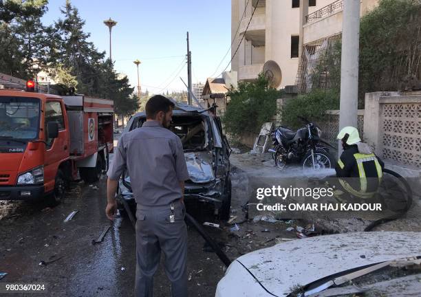 Members of the Syrian Civil Defence extinguish a destroyed car after a double explosion in the northern rebel-held city of Idlib on June 21, 2018.