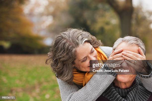 older woman covering husband's eyes - guess who stock pictures, royalty-free photos & images