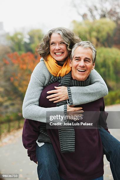 older man giving wife piggy back ride  - park couple piggyback stock pictures, royalty-free photos & images