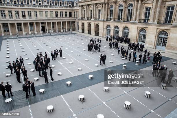 Security staff working for the Louis Vuitton fashion show stand at the Colonnes de Buren , an art installation created by the French artist Daniel...