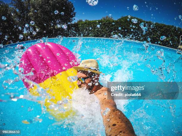 man falling in swimming pool with air mattress - cannonball diving stock pictures, royalty-free photos & images