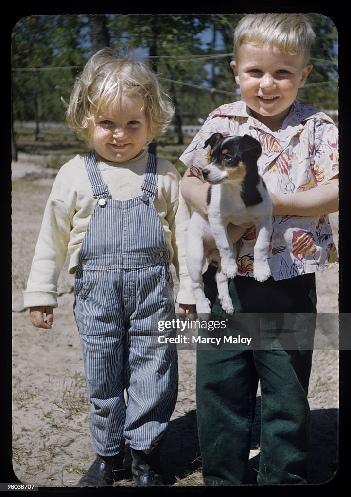 Blonde chubby toddlers hold puppy