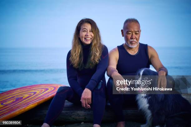 Japanese surfer family sitting with dog at early morning