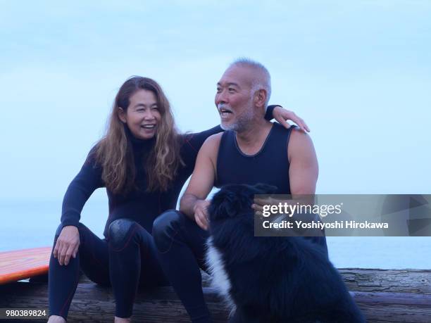 senior couple surfing early in the morning with surfboard - japanese couple beach stock-fotos und bilder