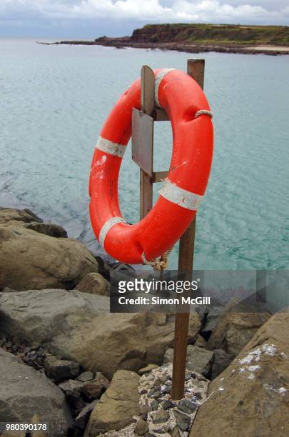 lifesaving ring on a metal stand on the breakwater at the mouth of lake illawarra and the tasman sea, new south wales, australia - ボラード ストックフォトと画像