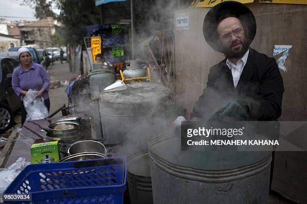 An ultra Orthodox Jewish man immerses cooking pots into boiling water to make it kosher for the Jewish festival of Pesah in a conservative Jerusalem...
