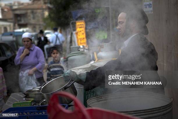 An ultra Orthodox Jewish man immerses cooking pots into boiling water to make it kosher for the Jewish festival of Pesah in a conservative Jerusalem...