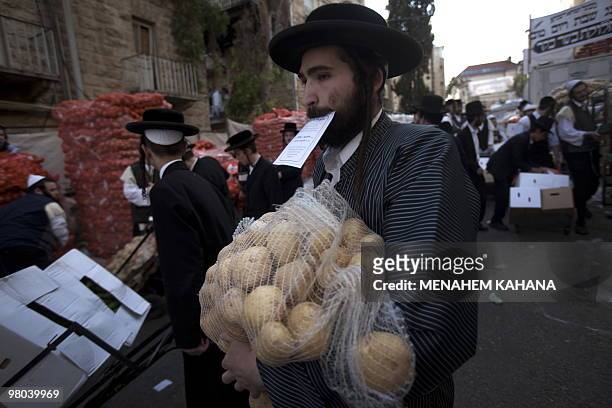 Ultra-Orthodox Jews carry donated food for poor families at a distribution center before Pesach holiday at a conservative Jerusalem neighbourhood on...
