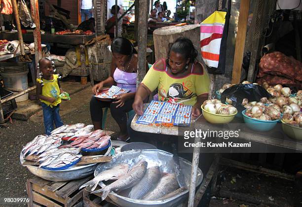 Women play a game of bingo while sat in the market place in downtown Buenaventura. Buenaventura is a port city and municipality located in the...