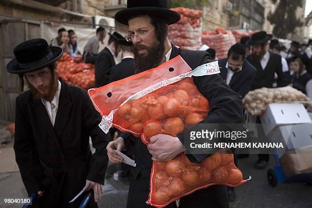 Ultra-Orthodox Jews carry donated food for the poor before Pesach holiday from a distribution center at their conservative neighbourhood in Jerusalem...