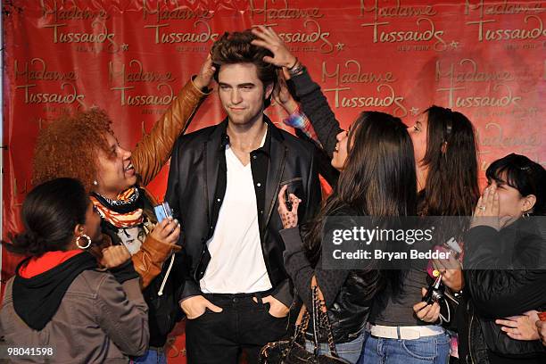 Fans pose for photographs with the Robert Pattinson wax figure during its unveiling at Madame Tussauds on March 25, 2010 in New York City.