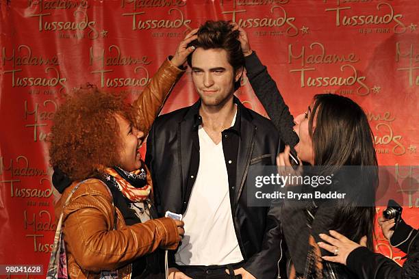 Fans pose for photographs with the Robert Pattinson wax figure during its unveiling at Madame Tussauds on March 25, 2010 in New York City.