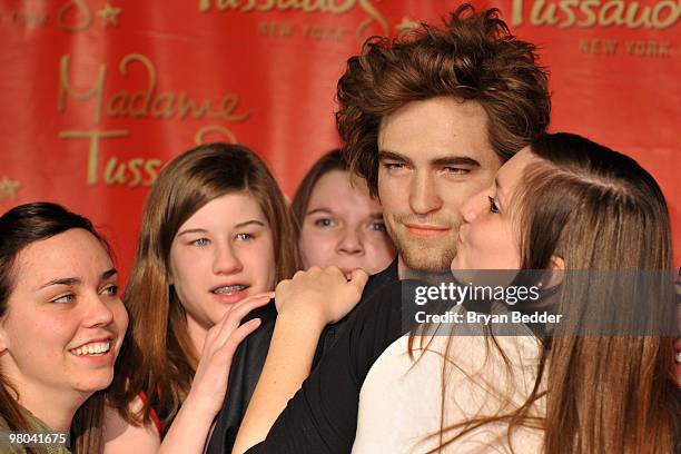 Fans pose for photographs with the Robert Pattinson wax figure during its unveiling at Madame Tussauds on March 25, 2010 in New York City.