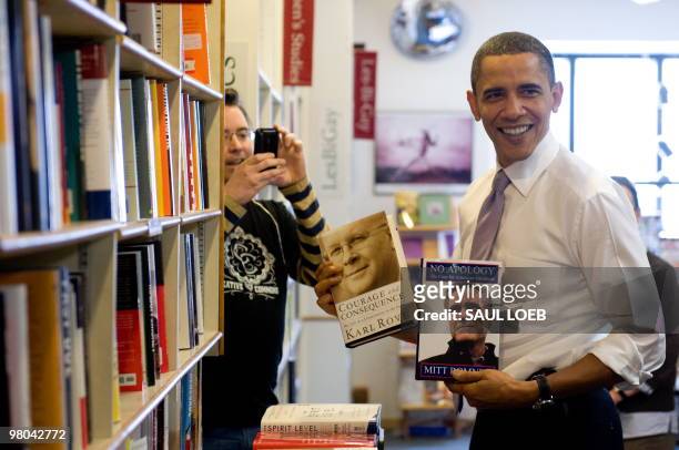 President Barack Obama holds up copies of Karl Rove's book and Mitt Romney's book at the Prairie Lights Bookstore during an unscheduled stop in Iowa...