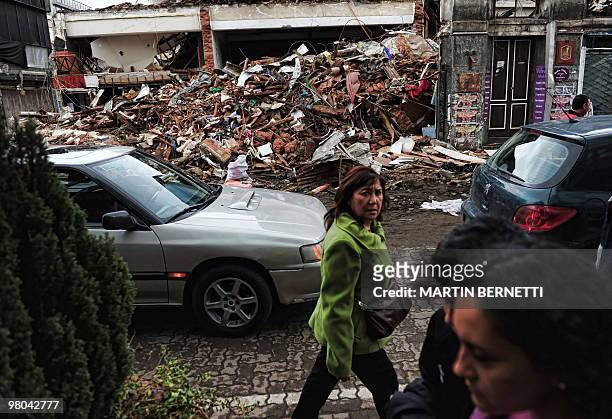 People passe by a collapsed house in Concepcion, some 500km south of Santiago, Chile, on March 23 after the February 27th earthquake. The massive...