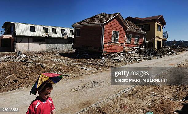 Boy plays next to a damaged house in Dichato seaside resort, some 460 km south of Santiago, that was damaged by the February 27th earthquake, on...