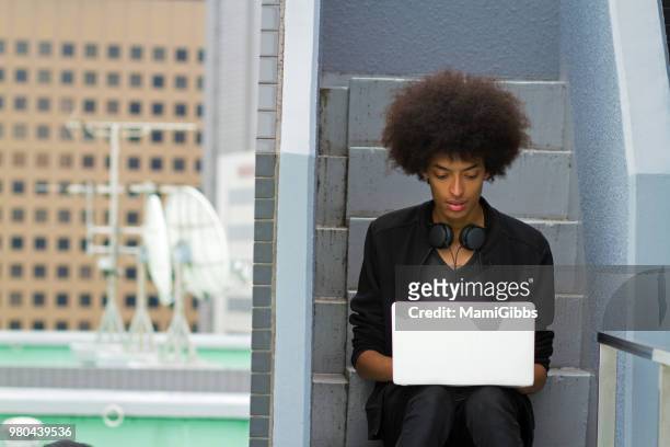 young man is working on a computer on the rooftop - mamigibbs stock pictures, royalty-free photos & images