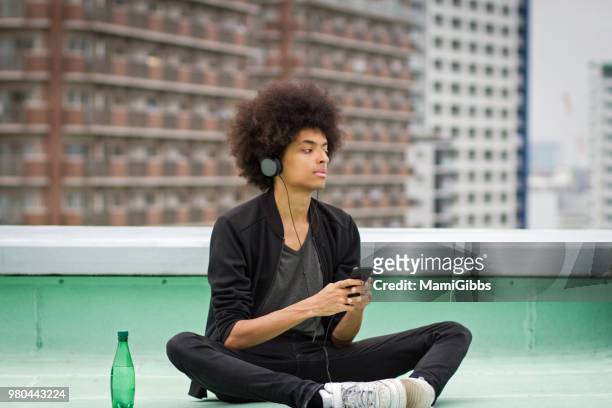 young man is relaxing on the rooftop - mamigibbs imagens e fotografias de stock