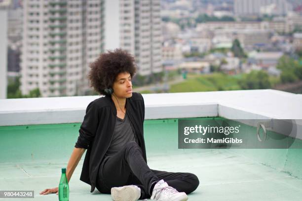 young man is relaxing on the rooftop - mamigibbs stock pictures, royalty-free photos & images