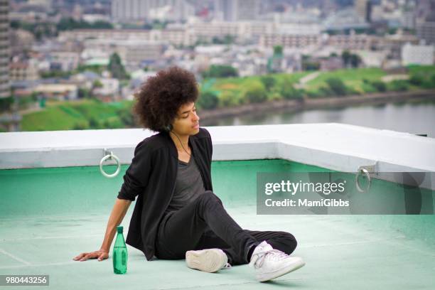 young man is relaxing on the rooftop - mamigibbs imagens e fotografias de stock