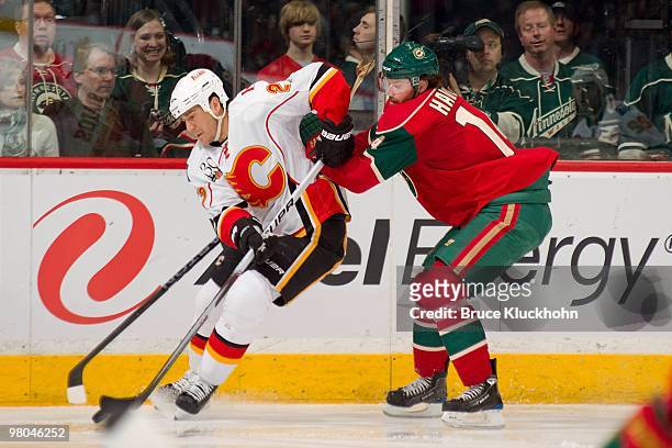 Steve Staios of the Calgary Flames handles the puck with Martin Havlat of the Minnesota Wild defending during the game at the Xcel Energy Center on...