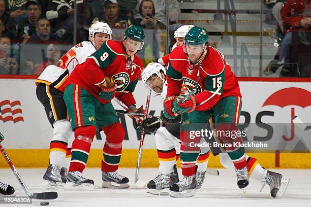 Mikko Koivu and Andrew Brunette of the Minnesota Wild skate for a loose puck with David Moss and Nigel Dawes of the Calgary Flames during the game at...