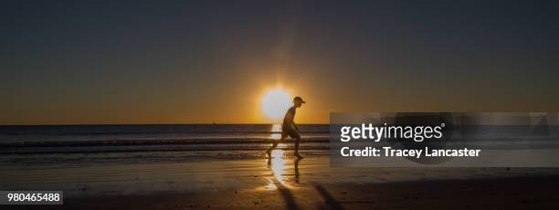 boy running on beach at sunset - cable beach stock-fotos und bilder