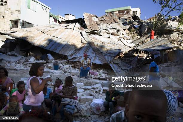 People sit outside their destroyed homes on January 14, 2010 in Port au Prince, Haiti. Destruction has devastated Port Au Prince and much of the...