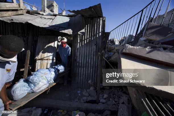 Men take a body out of a house on January 14, 2010 in Port au Prince, Haiti. As the world rallies to help, emergency efforts try and make way to the...